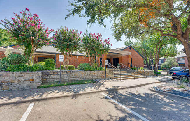 a brick building with trees and a sidewalk in front of it