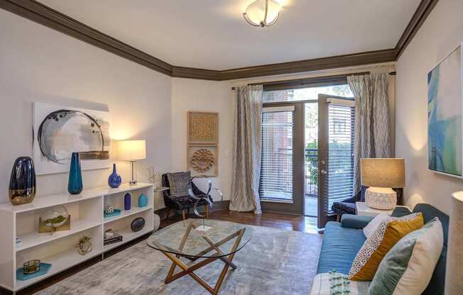 A living room with a blue couch and a glass coffee table.