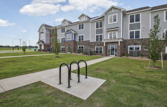 an apartment building with a bike rack on the sidewalk at Dodson Pointe Apartment Homes, Rogers