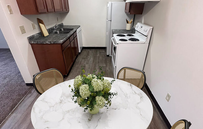 A kitchen with a white stove and a marble table with a vase of flowers on it.