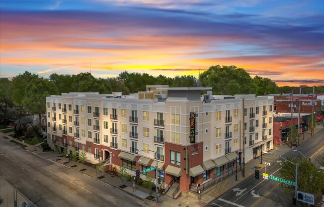 Corner view of West 39th Apartments in Kansas City, MO at sunset with modern architecture and retail-level frontage.