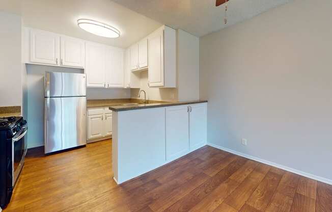 an empty kitchen with white cabinets and a stainless steel refrigerator