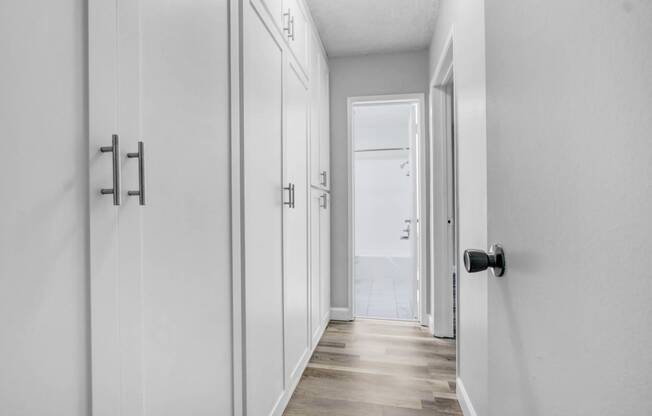 a white hallway with white closets and a door to the beach