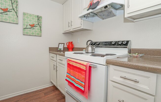 A kitchen with a white stove and white cabinets at Laurel Parc apartments in Shreveport, LA.
