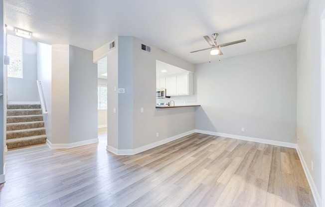 an empty living room and kitchen with hard wood floors