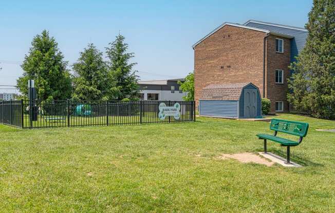 a park with a bench in front of a fence and a building