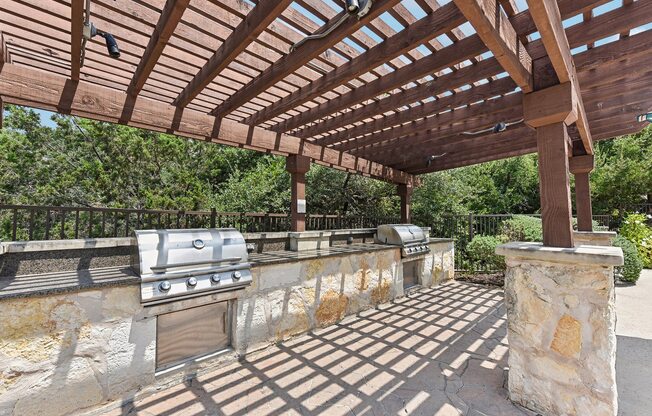 a patio with a barbecue grill and a pergola at Lakeline East Apartments, Cedar Park, 78613