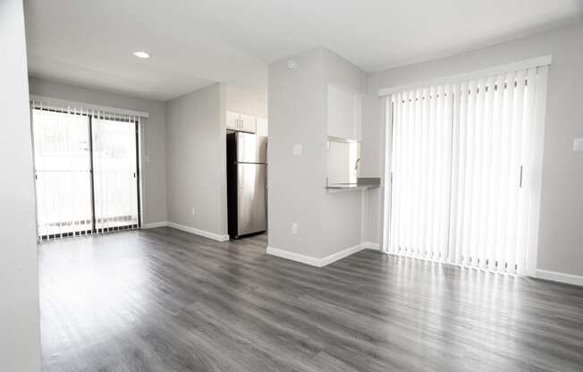 an empty living room with wood floors and a refrigerator