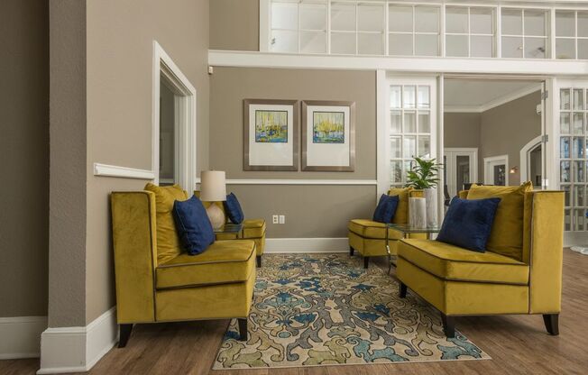 a living room with yellow couches and a blue rug