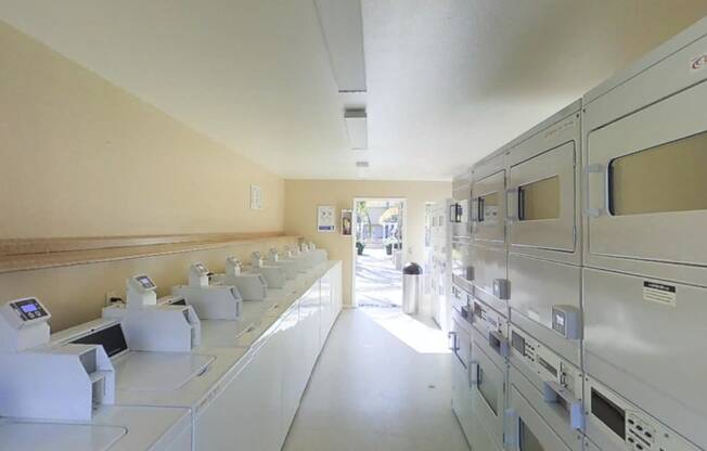 Laundry room view from back toward door with all machines in view