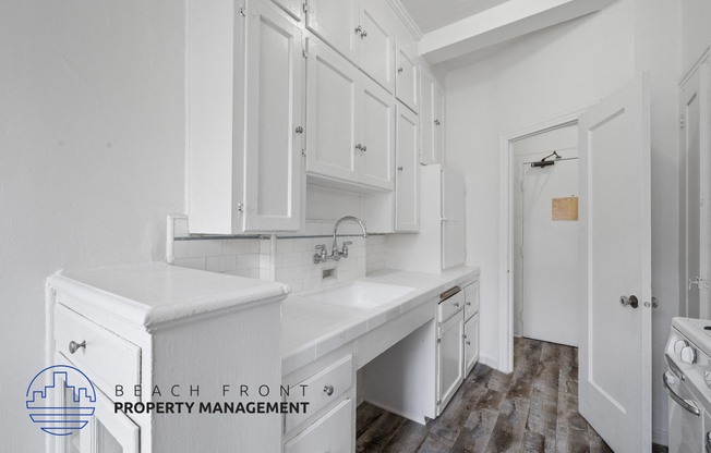 a white kitchen with white counters and white cabinets and a white door