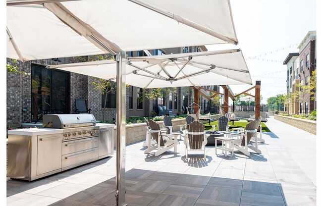 A patio with a grill and chairs under a white canopy.