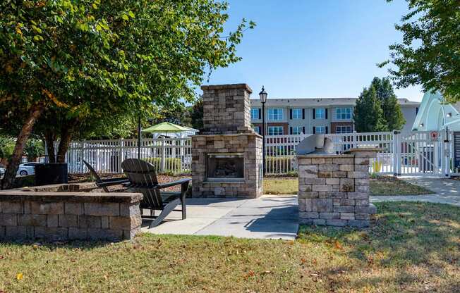 A park with a fireplace, bench and trees.