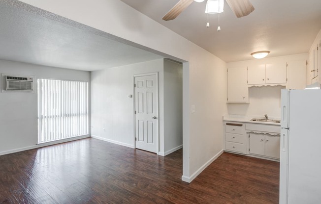 an empty living room and kitchen with a ceiling fan