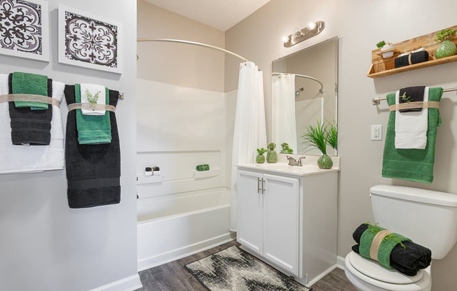 Spacious bathroom with vinyl flooring, a curved shower rod, white storage cabinets and soaking tub at The Summit on 401.