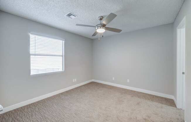 an empty room with a ceiling fan and a window