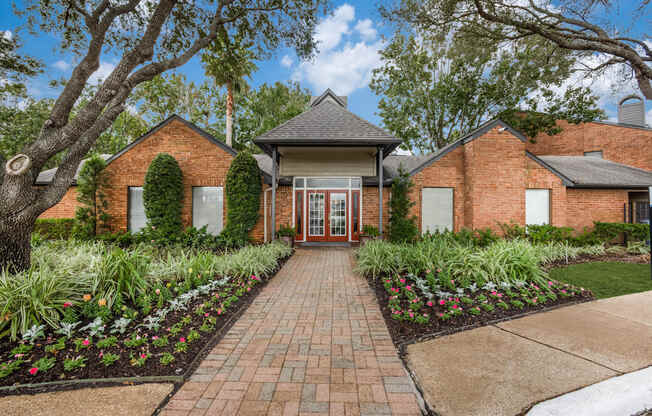 the front of a brick house with a brick pathway and landscaping