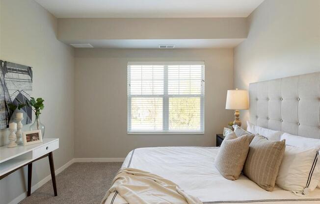 A bedroom with a large bed and a window with blinds.