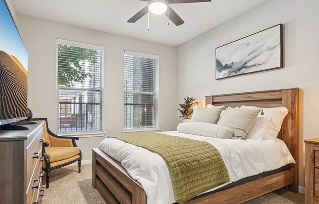 A bedroom with a bed, chair, and a television.