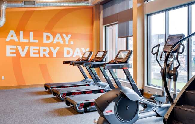 a row of treadmills in front of a wall with the words all day every day