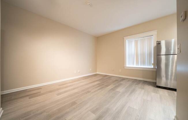 A room with a wooden floor and a window with white curtains.