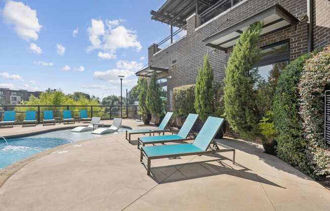 A pool with lounge chairs and a building in the background.