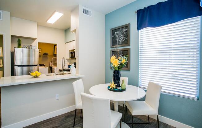 a dining area with a table and chairs and a kitchen in the background