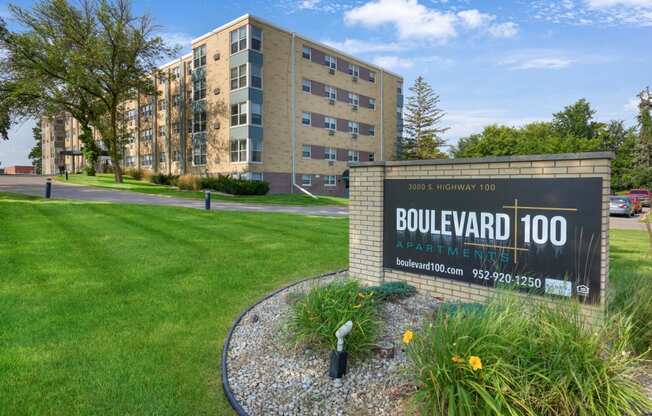 a sign for the boulevard 100 apartment complex in front of a green grass field