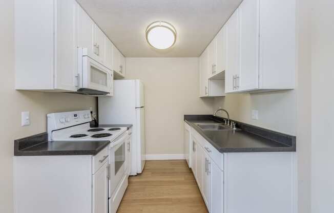 One-Bedroom Apartments in Redwood City, CA - Avenue Two - Kitchen with Granite Countertops, White Cabinets, White Appliances, and Hard Surface Flooring at Avenue Two Apartments, Redwood City  , CA