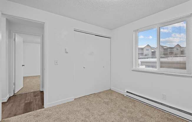 A room with a carpeted floor and a window with blinds.