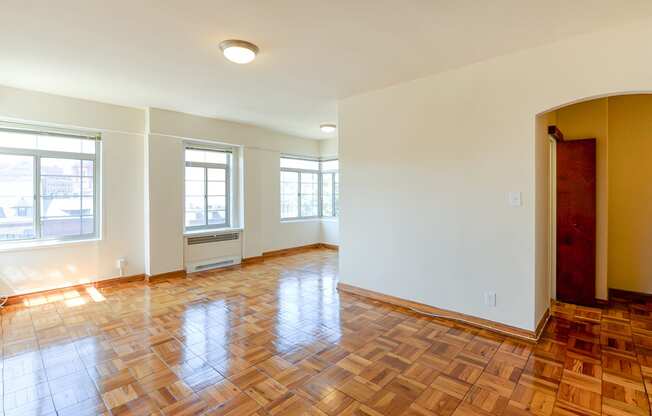 vacant living area with hardwood flooring, large windows and view of entrance at the baystate apartments in washington dc