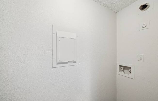 A white wall with a white electrical outlet and a white door.
