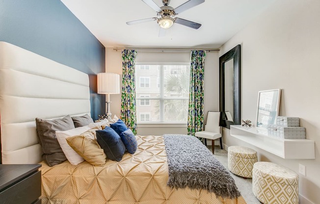 A bedroom with a bed, a chair, a window, and a ceiling fan.