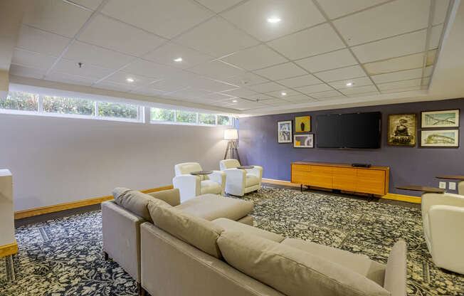 A living room with a couch, chairs, and a television.
