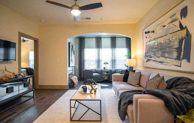 A living room with a couch, a coffee table, and a ceiling fan.