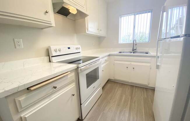 an empty kitchen with white appliances and white cabinets