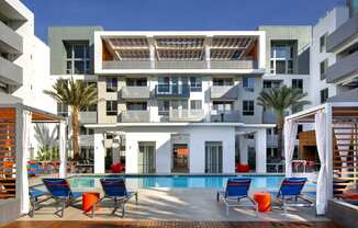 a building with a pool and chairs in front of it