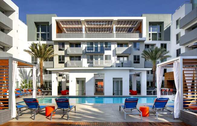 a building with a pool and chairs in front of it