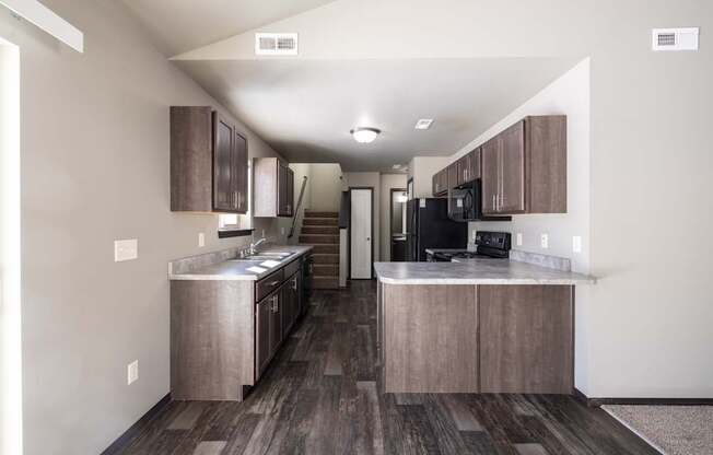A kitchen with wooden floors and a black refrigerator.