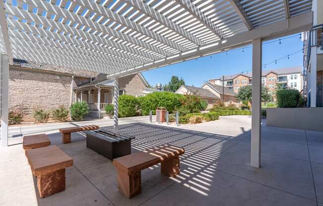 a covered patio with benches and a fire pit