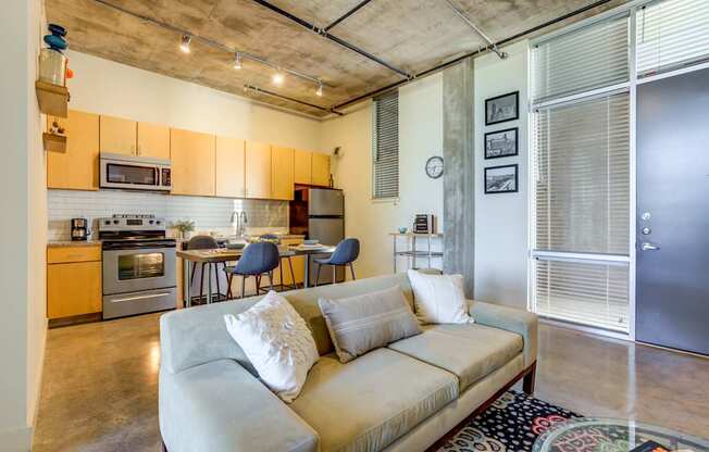 A living room with a couch and a kitchen area in the background.