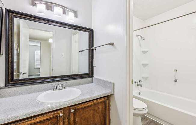 A bathroom with a white tub, sink, and mirror.