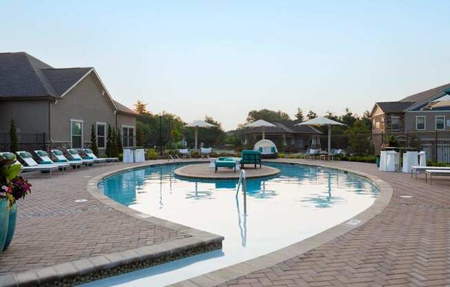 A large outdoor swimming pool surrounded by lounge chairs and umbrellas.