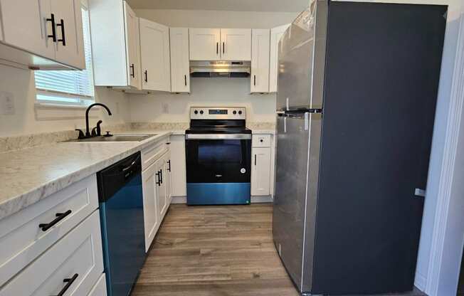 a kitchen with white cabinets and a black refrigerator