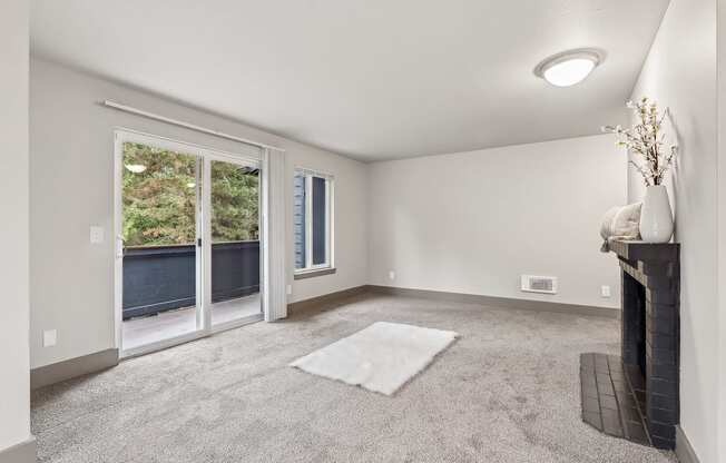 A living room with a grey carpet and a fireplace.
