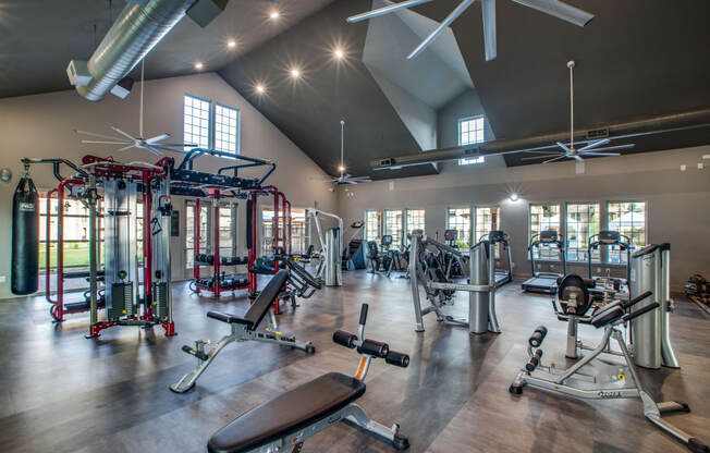 a spacious fitness center with exercise equipment and windows
