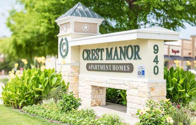 Crest Manor Apartment Homes sign with a stone pillar and a green lawn.
