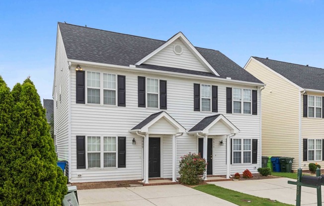 a white house with black shutters and a driveway