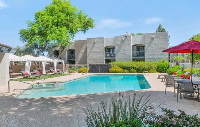 a swimming pool with chairs and umbrellas and a building in the background