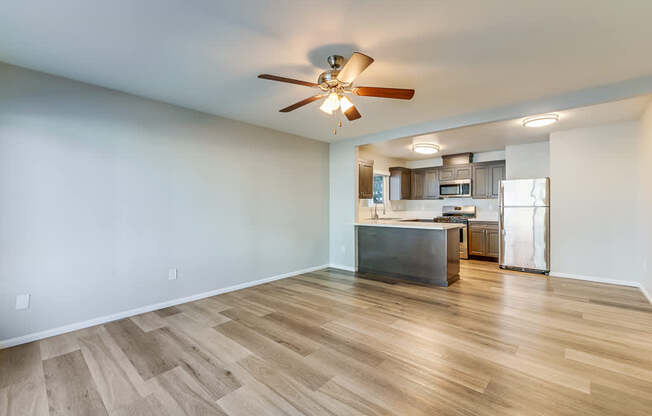 A room with a ceiling fan and wooden flooring.